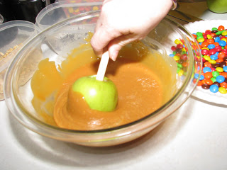 dipping apple into melted caramel