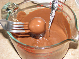 Dipping cake truffle into melted chocolate candy melts 
