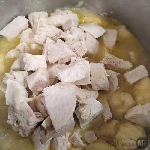 adding chicken to biscuits cooking in broth