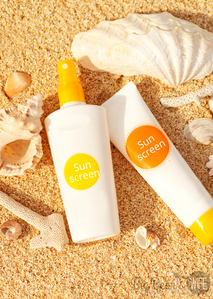 White bottles of Sunscreen on sand with seashells