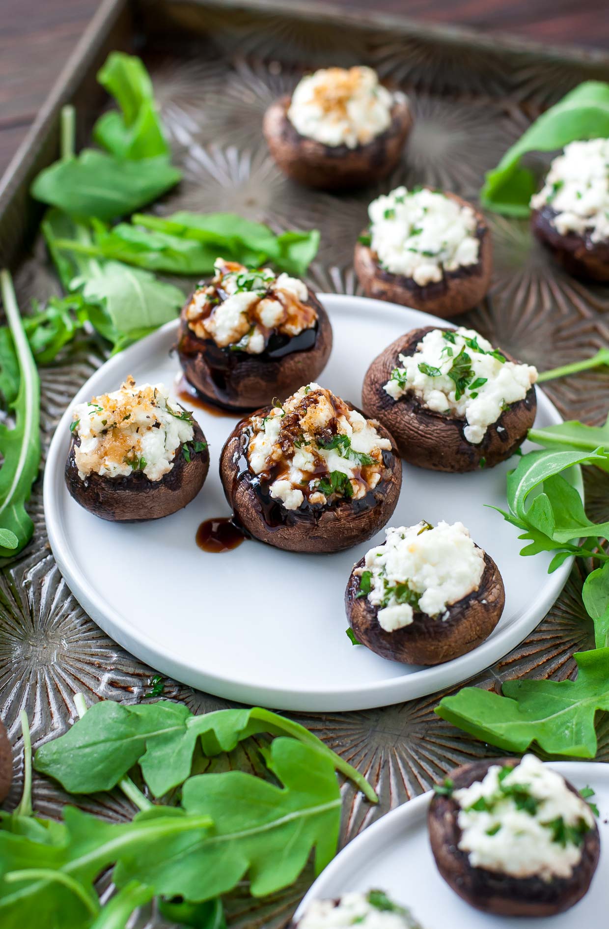 Let's jazz up our appetizer game! These herbed goat cheese stuffed mushrooms are piled high with savory whipped goat cheese, spiked with fresh herbs, and drizzled with a sweet + savory balsamic reduction to make them over-the-top delicious.