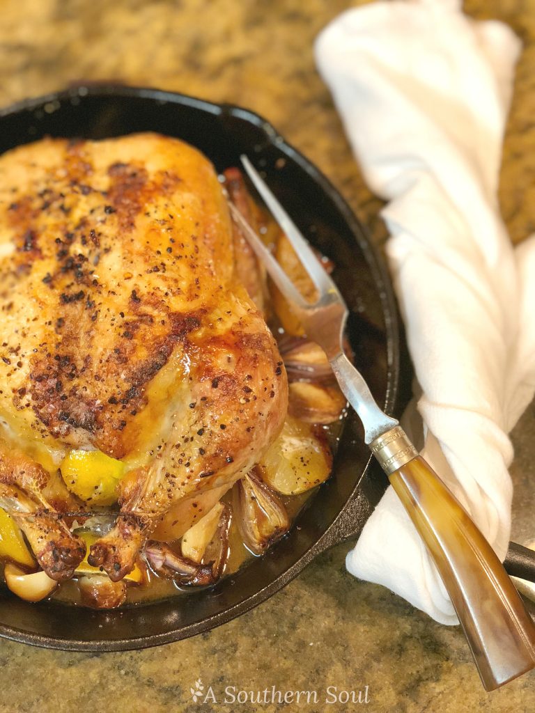 juicy tender lemon roast chicken in cast iron with onions and garlic