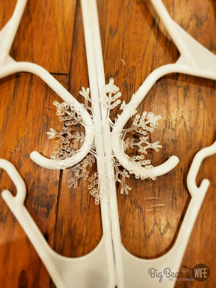 glueing small snowflake onto DIY Dollar Tree Snowflake Clothes Hanger Craft