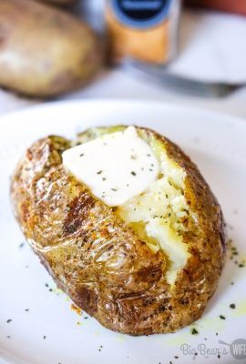 Baked Potato Cut open on white plate with butter and parsley