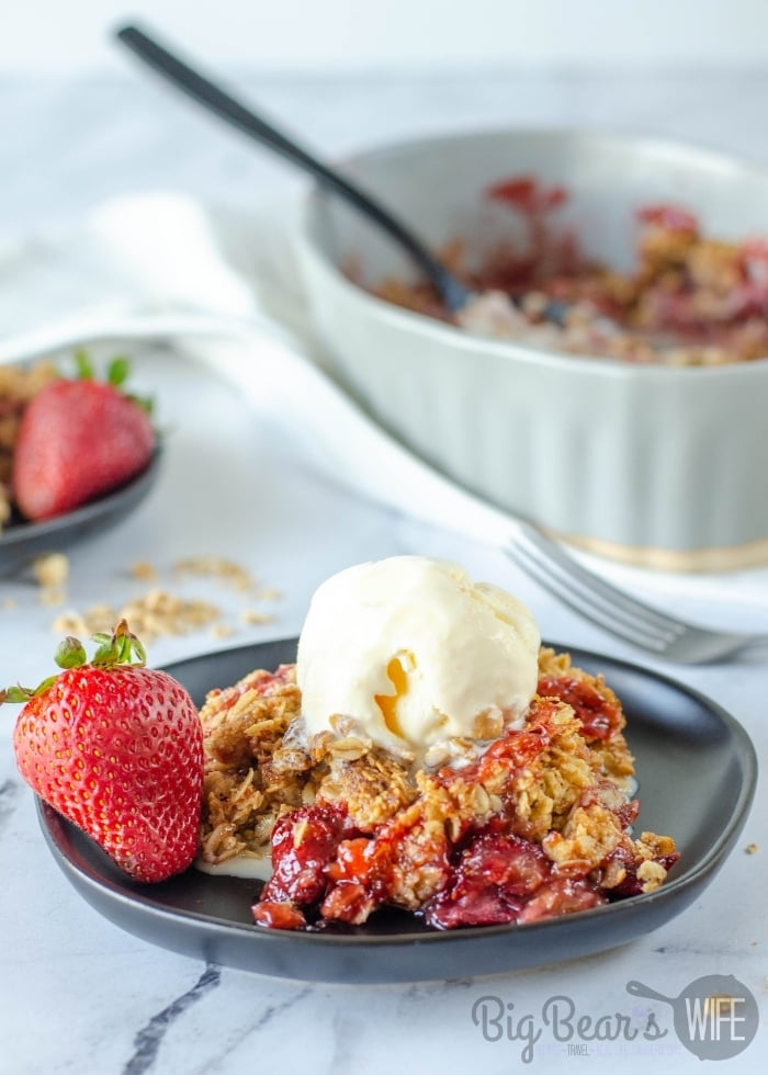 Homemade Strawberry Cobbler with a scoop of vanilla ice cream on black plate
