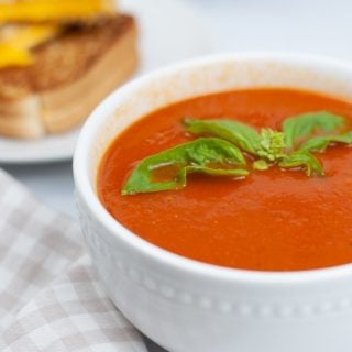 INSTANT POT TOMATO SOUP in white bowl with grilled cheese in back ground