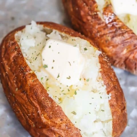 air fried baked potato cut open with a pat of butter and dried parsley