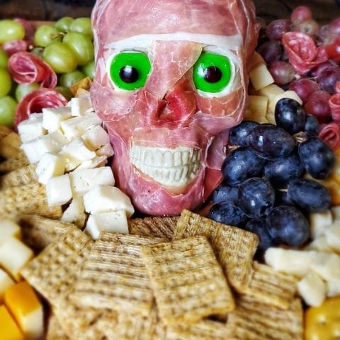 Easy Meat Skull Party Tray - a Halloween charcuterie board with a scary skull covered in prosciutto, surrounded by grapes, cheese and salami is the perfect board for Halloween!
