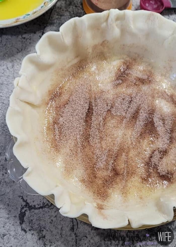 Cinnamon Sugar sprinkled over Melted Butter Brushed on Pie Crust In Pie Plate