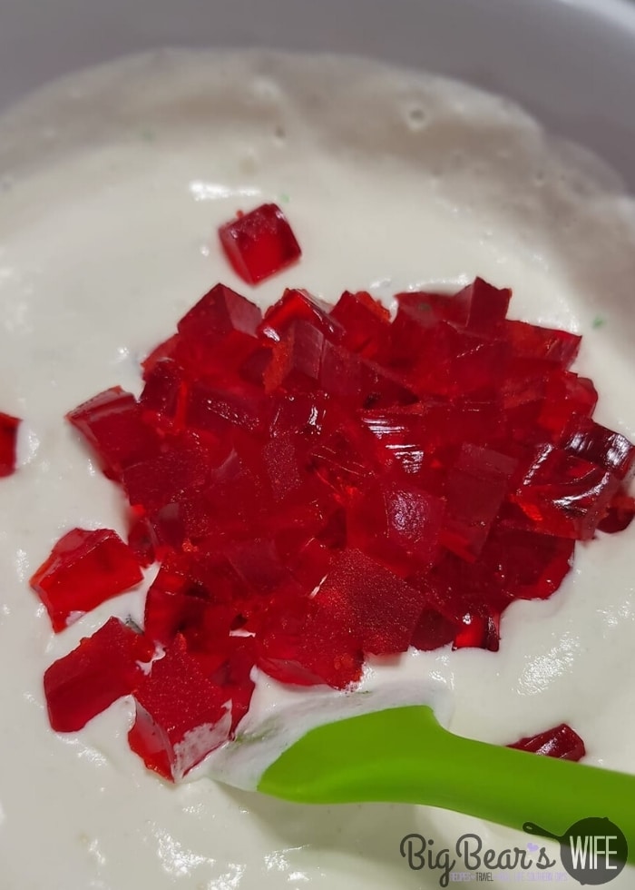 Adding red Jell-O squared to pineapple whipped topping mixture