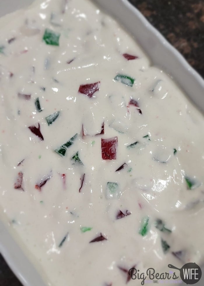 Red and Green Jell-O squares in whipped topping in a white casserole dish