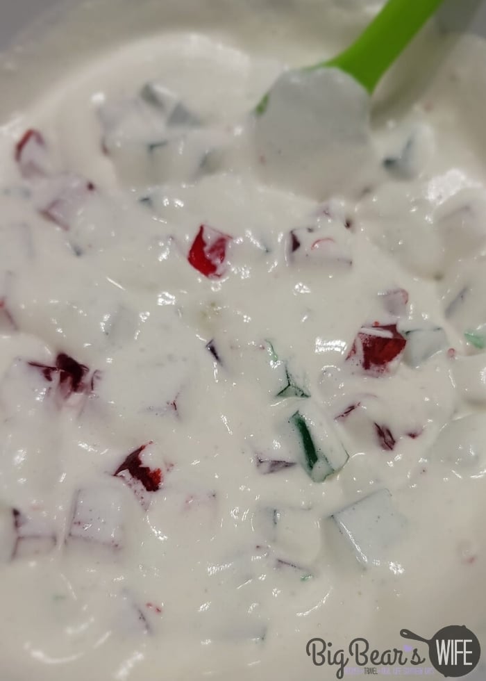 stirring together green and red Jell-O squares to pineapple whipped topping mixture