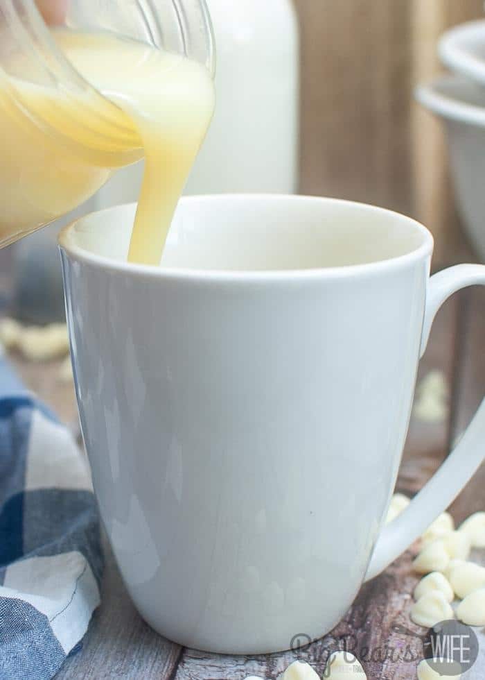 pouring Homemade White Chocolate Syrup into a white mug