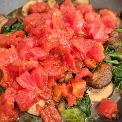 Mushrooms, diced tomatoes and spinach in a skillet