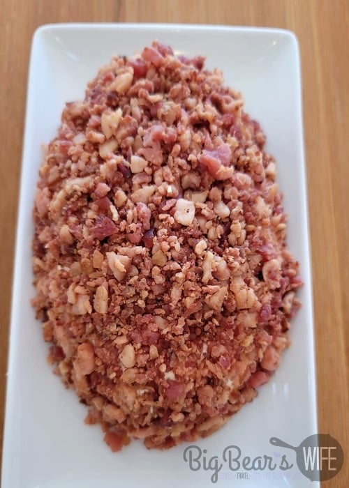 cheeseball mixture shaped into a football covered in bacon