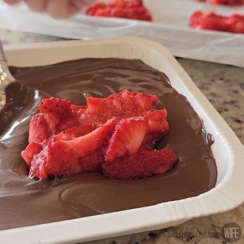covering frozen mashed strawberries in chocolate